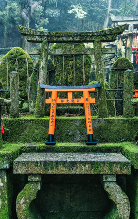 Small shinto place of worship with Torii Gates and inscriptioned stones at Fushimi Inari Taisha temple in Kyoto, Japan. ( Japanese inscriptions translated are different religion blessings)の写真素材