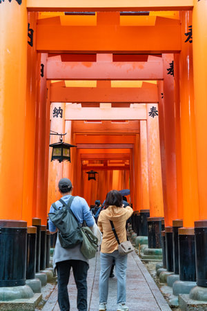 Tourists walking through the torii gate covered walking path at Fushimi Inari Taisha temple in Kyoto, Japan.の写真素材