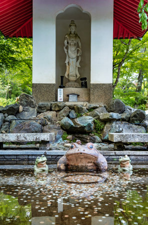 Small pond with many coins and a frog statue in a japanese garden. Lucky frog on the grounds of Tenryu-ji temple, Kyoto.の写真素材