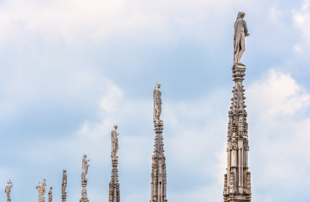 View of the gothic ornate spires and statues adorning the rooftop of the Milan Cathedral (Duomo di Milano) in Italy.の写真素材