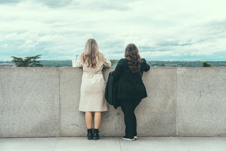 Two unidentifiable women stand side by side enjoying the scenic view from the Royal Palace Viewpoint in Madrid, Spainの写真素材
