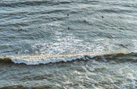 View from above with surfers riding the waves of the Pacific coast in Lima, Peru.の写真素材