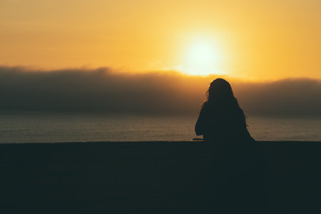 Silhouette of a woman with long hair admiring the sunset from a Miraflores viewpoint over the Pacific Ocean in Lima, Peruの写真素材