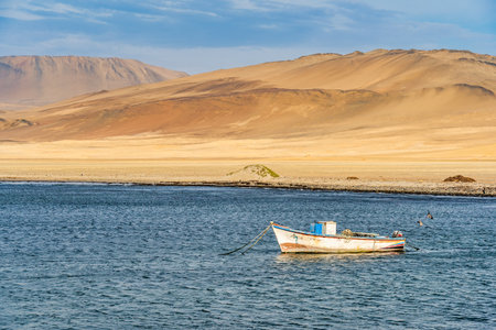 A tranquil scene with a fishing boat floating in the calm waters of Pacific Ocean at Paracas National Reserve, Peru.の写真素材