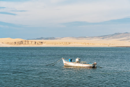 A tranquil scene with a fishing boat floating in the calm waters of Pacific Ocean at Paracas...
