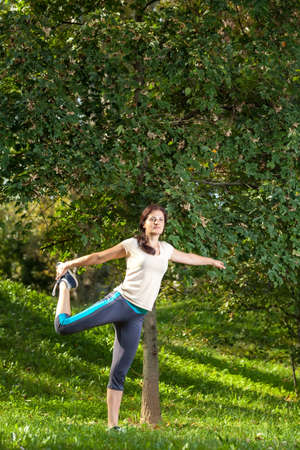 woman doing exercise in park under a treeの写真素材