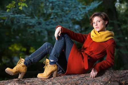 Sexy beautiful serious romantic girl with short hair stand on a log in autumn dayの写真素材