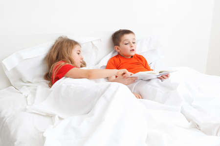 brothers girl and boy reading a book in bed before sleepの写真素材