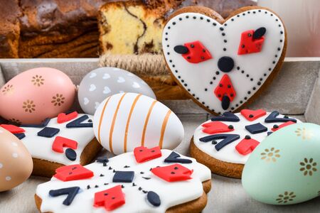 Slices of Romanian sponge cake with red traditional towel with manual stitch on wooden board, Easter painted eggs and home made ginger bread hearts, Authentic Easter Brunch concept.の写真素材