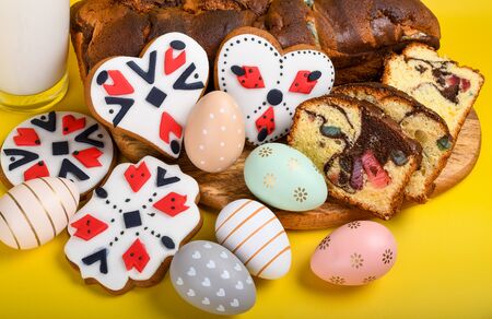 Slices of Romanian sponge cake with red traditional towel with manual stitch on wooden board, Easter painted eggs and home made ginger bread hearts, Authentic Easter Brunch concept.の写真素材