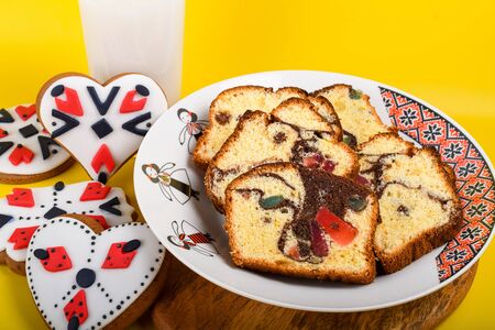 Slices of Romanian sponge cake with red traditional towel with manual stitch on wooden board, Easter painted eggs and home made ginger bread hearts, Authentic Easter Brunch concept.の写真素材