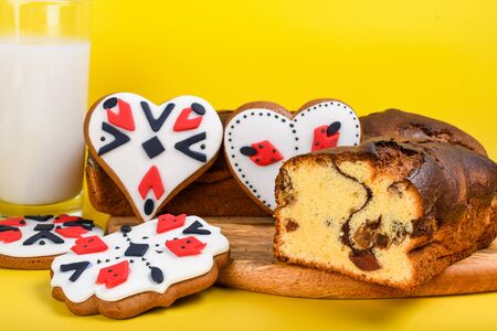 Slices of Romanian sponge cake with red traditional towel with manual stitch on wooden board, Easter painted eggs and home made ginger bread hearts, Authentic Easter Brunch concept.の写真素材