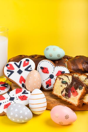 Slices of Romanian sponge cake with red traditional towel with manual stitch on wooden board, Easter painted eggs and home made ginger bread hearts, Authentic Easter Brunch concept.の写真素材