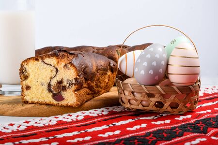 Slices of Romanian sponge cake with red traditional towel with manual stitch on wooden board, Easter painted eggs and home made ginger bread hearts, Authentic Easter Brunch concept.の写真素材