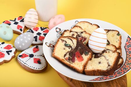 Slices of Romanian sponge cake with red traditional towel with manual stitch on wooden board, Easter painted eggs and home made ginger bread hearts, Authentic Easter Brunch concept.の写真素材