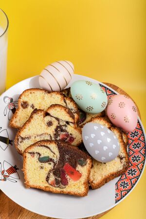 Slices of Romanian sponge cake with red traditional towel with manual stitch on wooden board, Easter painted eggs and home made ginger bread hearts, Authentic Easter Brunch concept.の写真素材