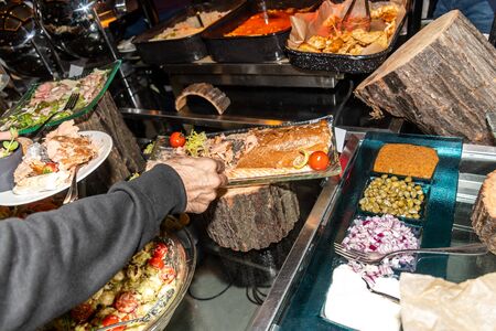 People around table during brunch buffet with hands, putting foods on plate. Food Buffet Catering Dining Eating Party Sharing Concept. Restaurant display of many international dishes, variety of foodの写真素材