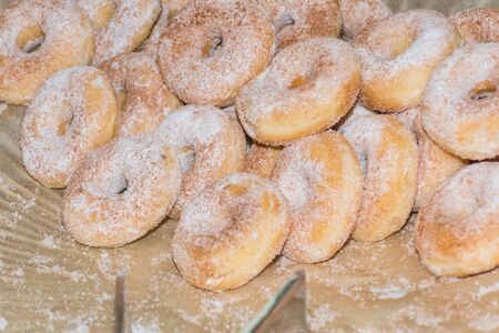 Stack of fresh and sweet powder sugar glazed hole round doughnuts on a plate during brunch or catering event. Pastry dessert homemade and delicious breakfast baked snack foodの写真素材