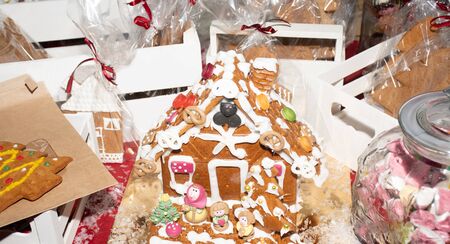Handcrafted Christmas gingerbread house on red velvet. European Christmas holiday traditions. Christmas holiday sweets and gifts on a candy bar table display. homemade traditional dessertの写真素材