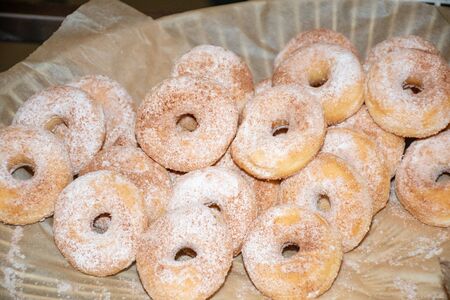 Stack of fresh and sweet powder sugar glazed hole round doughnuts on a plate during brunch or catering event. Pastry dessert homemade and delicious breakfast baked snack foodの写真素材