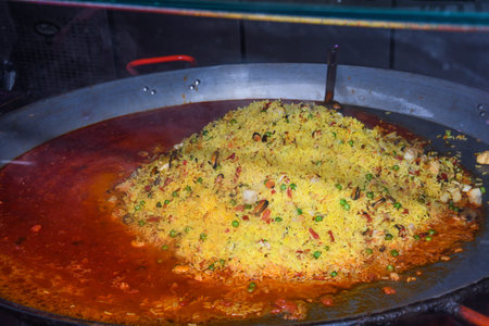 Seafood paella cooked in a large pan wok, street food festival. Mexican fiesta national day dish...