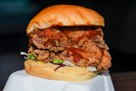 Fresh melting burger ready to eat during fast food festival. Outdoor catering event, brunch or outside dinner party with fast food. Melting cheese and golden bun. Appetizing closeup homemade burgerの写真素材