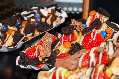 Street food dessert: waffles and small pancakes with varied toppings and fruits on top. Fresh Food Buffet Brunch Catering Dining Eating Party Sharing Conceptの写真素材