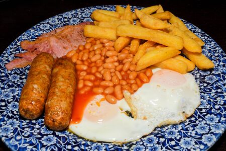 Traditional full English breakfast with fried eggs, sausages, beans, mushrooms, grilled tomatoes and bacon on wooden background. Top viewの写真素材