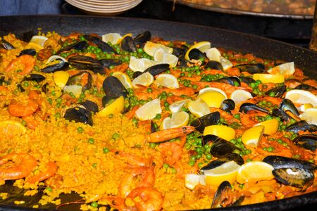 Seafood paella cooked in a large pan wok, street food festival. Mexican fiesta national day dish specialty. Live cooking station. Fresh Food Buffet Brunch Catering Dining Eating Party Sharing Conceptの写真素材