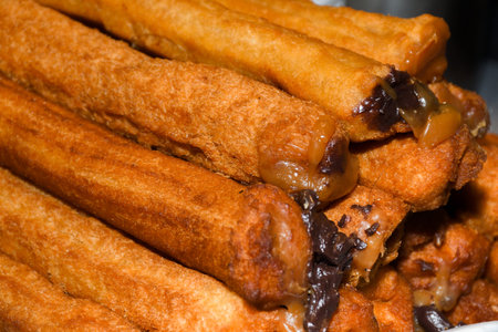Churros with sugar powder and cinnamon in melted chocolate dip.