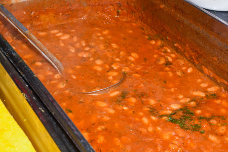 Beans stew, chili sin carne, large pot on fire cooking during food festival. Ready kettle beans after four hours cooking time over an open wood fire. With tomatoes, onions, tomatoes, red peppersの写真素材