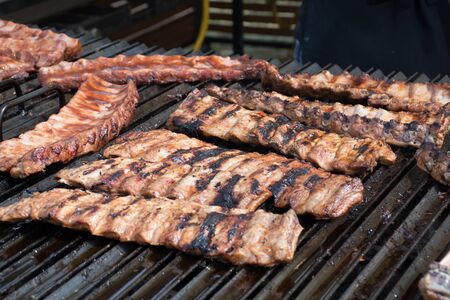 Chef cooking fresh pork ribs on the charcoal grill, during food festival, street food or food market, food truck.の写真素材