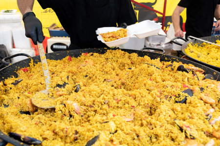 Seafood paella cooked in a large pan wok, street food festival. Mexican fiesta national day dish specialty. Live cooking station. Fresh Food Buffet Brunch Catering Dining Eating Party Sharing Conceptの写真素材