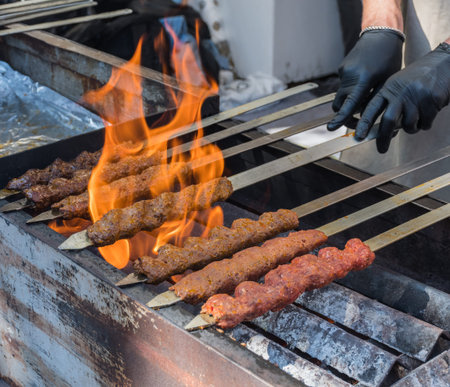 Adana kebab (ground lamb minced meat on skewer on grill over charcoal).Chef preparing traditional...