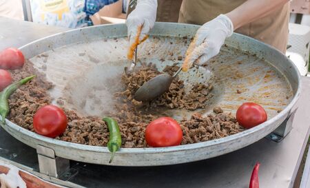 Traditional Turkish shawarma meat being prepared with red tomatoes and red and green peppers, available for sale at a street food market, selective focusの写真素材