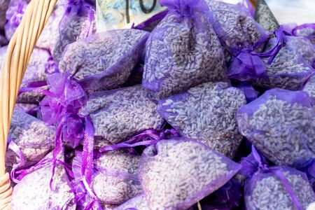 Pouch with lavender in a wooden basket. Fragrant bag of lavender flowers. Sprigs of lavender near the bag with Lavender. Selective focus. Street market.の写真素材