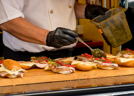 Chef preparing sandwich, live cooking session. Fast food festival, street food. Bacon, chicken,...