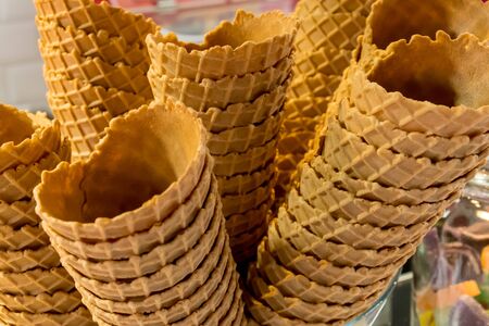 Crispy golden empty ice cream cones one over another, in a candy shop, during fast food festival. Sweet treat, gluten free, lactose free, sugar free, bio and organic productの写真素材