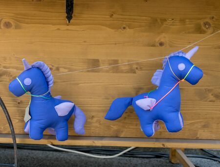 Purple unicorn toy hanging on a rope on a van during food festivalの写真素材