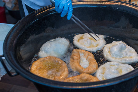 Homemade traditional hungarian dish named "langosi" during food festival, freshly baked or deep fried stack of doughnuts, on a plate, on a rustic napkin table setting. Fast food snack, sweet or saltyの写真素材