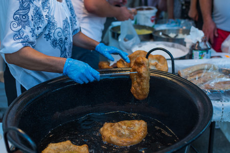 Homemade traditional hungarian dish named "langosi" during food festival, freshly baked or deep fried stack of doughnuts, on a plate, on a rustic napkin table setting. Fast food snack, sweet or saltyの写真素材