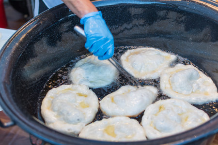 Homemade traditional hungarian dish named "langosi" during food festival, freshly baked or deep fried stack of doughnuts, on a plate, on a rustic napkin table setting. Fast food snack, sweet or saltyの写真素材