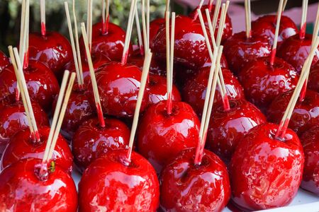 Sweet glazed red toffee candy apples on sticks for sale on farmer market or country fair. Thanksgiving and Halloween homemade red caramel glazed toffee apples with sticksの写真素材