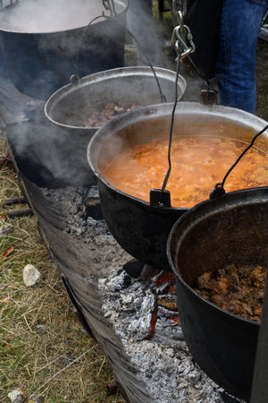 Very large cauldron cooking food during campfire, big pots on fire preparing during food festival....