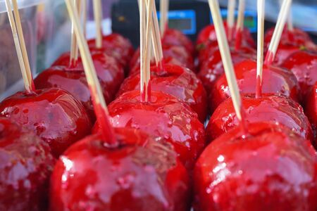 Sweet glazed red toffee candy apples on sticks for sale on farmer market or country fair. Thanksgiving and Halloween homemade red caramel glazed toffee apples with sticksの写真素材