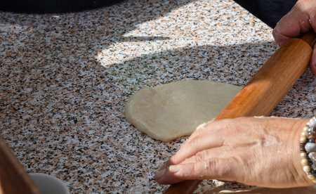 Woman hands rolling dough with rolling pin, making pies or pizza bread, homemade
