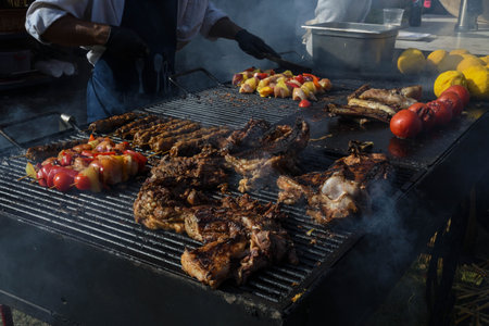Chef grilling meat during cookout picnic or food event. Meat mix variety:sausages, pork, chicken,...