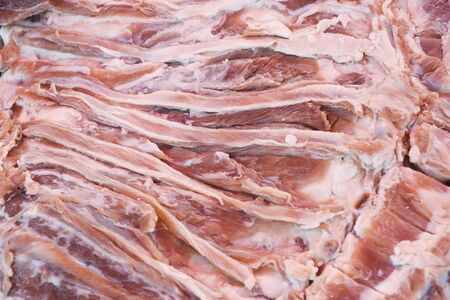 Fresh and raw sheep or lamb meat pieces for sale on the counter top of a butchery shop. Uncooked protein with fat and red flesh, closeup macro isolated outside marketplaceの写真素材