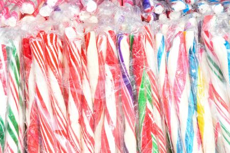 Round multi colored spiral lollipop display for sale. Christmas treats concept for kids. Happy yellow, green, blue, orange swirl candyの写真素材