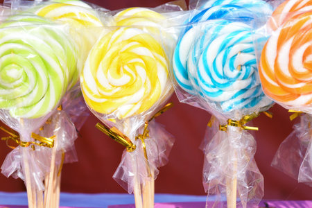 Round multi colored spiral lollipop display for sale. Christmas treats concept for kids. Happy...